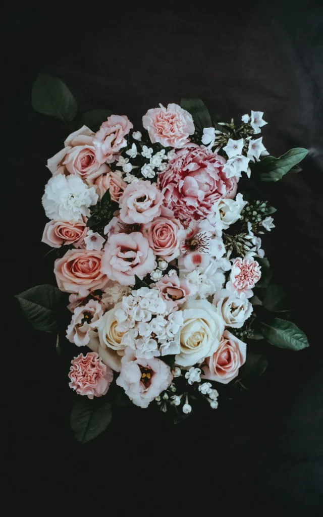 Composition florale d'hommage composée de roses roses et de fleurs blanches.